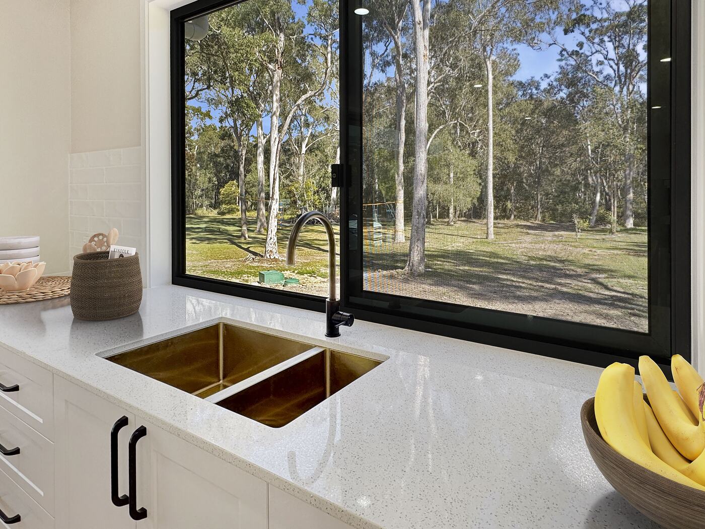 Double sink set into the stone benchtop below a wide window
