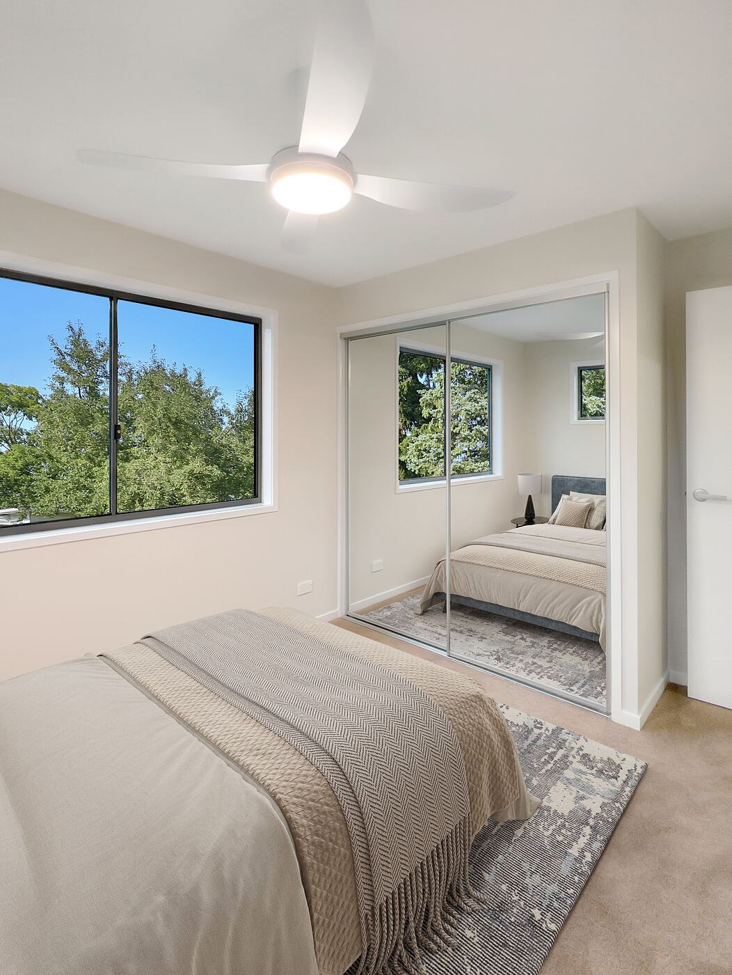 Second bedroom with a mirrored robe and treetop views